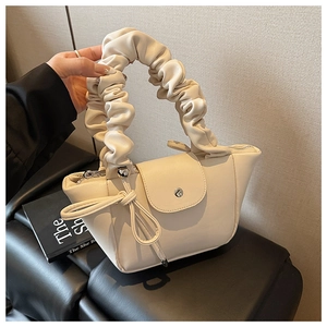 Detail of cream pleated handle and bow drawstring on a PU leather handbag