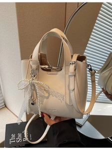 Chic beige leather bucket bag with lace bow and pearl charm for elegant women