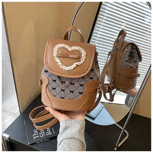 Close-up of khaki leather backpack featuring lace heart and gingham ribbon details