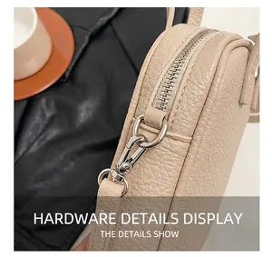 Detail view of silver metal hardware and lychee pattern leather on beige crossbody bag