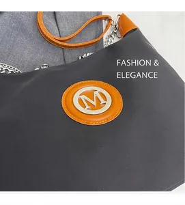 Detail of black fabric bag with orange leather logo patch and silver chain strap