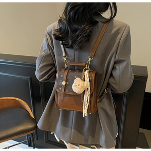 Detail of vintage brown monogram backpack featuring a plush bear charm and striped scarf