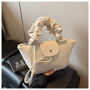 Detailed view of the cream white pleated scrunchie handle and silver metallic clasp on handbag