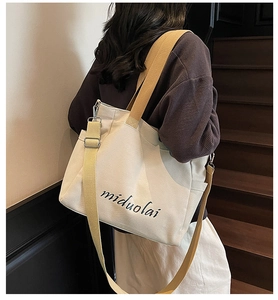 Detail view of canvas tote bag with adjustable strap and cursive letter print