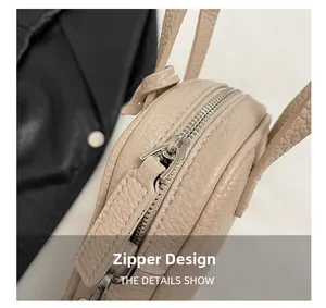 Detail view showing the silver metal zipper closure and litchi texture on the beige bag