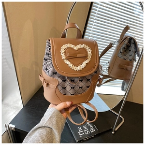 Detail of caramel brown backpack with heart lace, leather bows and mirror reflection