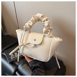 Detail of creamy white pleated handbag showing gathered handle and drawstring knot