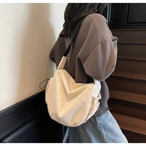 Detailed view of cream canvas crossbody bag featuring adjustable black wide shoulder straps