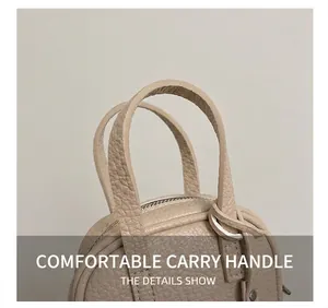 Detail view of the beige small square bag featuring comfortable double handles and zipper