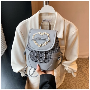 Close-up of mini grey backpack with lace heart, bow detail, and plaid pattern side panels