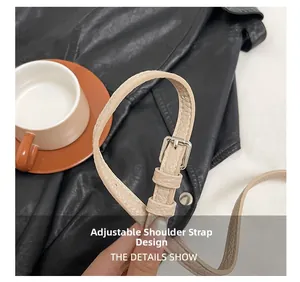 Detail of beige adjustable shoulder strap with silver metal buckle on a stylish bag