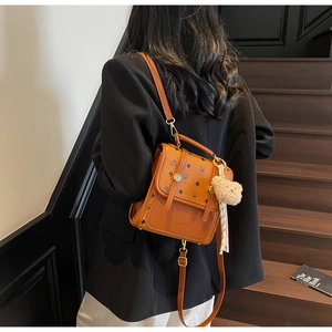 Detail of caramel mini backpack featuring bear print canvas and plush bear charm