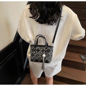 Detail of a chic bucket bag with geometric maze pattern and long tassel charm