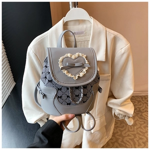 Close-up of mini grey backpack with lace heart, bow detail and checkered pattern