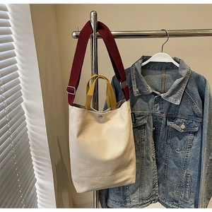 Détail du sac cabas en toile avec bandoulières bicolores, fermoir aimanté et étiquette