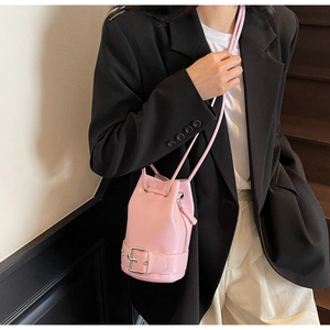 Détail du sac seau rose à cordon avec boucle et fermeture éclair porté par le mannequin