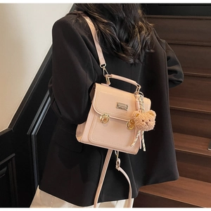 Detail of pink fashion backpack with gold twist locks and cute brown bear pendant