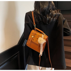 Detail view of brown vintage leather satchel with bear pattern and plush bear charm