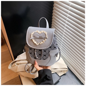 Detail of a mini grey backpack featuring a lace heart and black gingham patterns