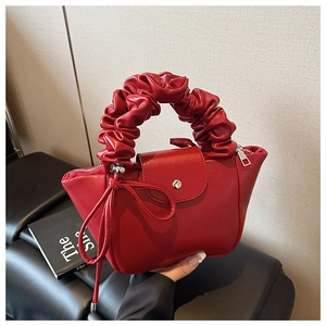 Close-up of red ruched handle handbag with metal clasp and elegant leather texture
