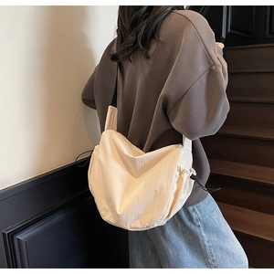 Detail of cream canvas dumpling bag with drawstring closure and wide strap