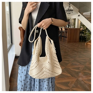 Detail of bohemian cream crochet tote bag with fringe accents and hollow weave texture