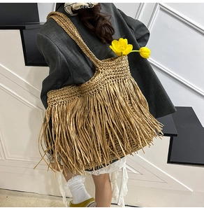 Détail d'un grand sac cabas en paille avec des franges pour style de plage