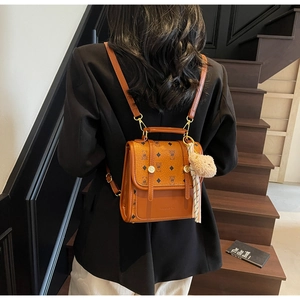 Detail of brown mini backpack featuring diamond bear print and teddy bear charm on stairs