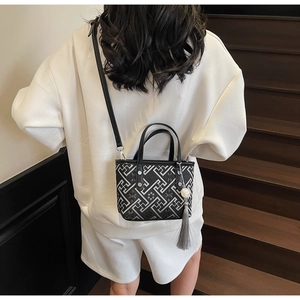 Detail of crossbody bucket bag with geometric print, tassel charm and leather strap