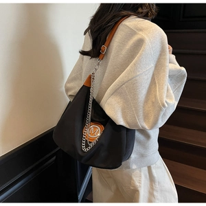Detail of black nylon crossbody bag with orange logo patch and metallic chain strap
