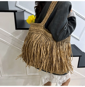 Détail d'un sac bandoulière en paille bohème avec longues franges et tissage