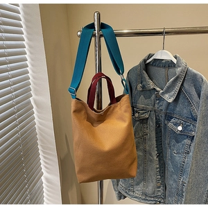 Détail du sac cabas en toile avec bandoulière bleue et poignée rouge contrastée