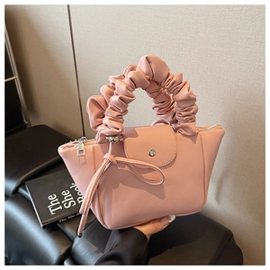 Detail of pink pleated handle and decorative knotted tassel on the stylish PU leather handbag