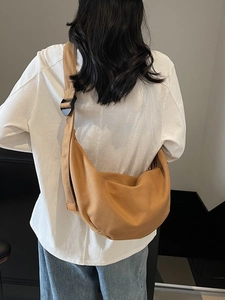 Brown canvas half-moon crossbody bag with wide shoulder strap in a minimalist casual style