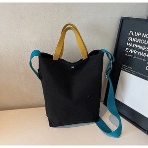 Détail du sac cabas en toile bicolore avec poignées jaunes et bretelles bleues réglables