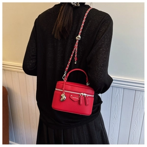 Details der roten Koffer-Tasche aus Leder mit Gliederkette und Herz-Anhänger