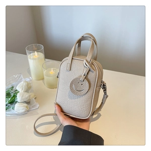 Detail of grey pebble leather handbag with silver hardware and smiley face charm