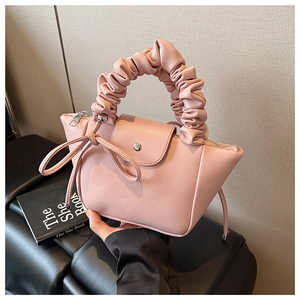 Detail of pink PU leather handbag featuring pleated cloud handle and bow decoration