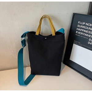 Détail du sac fourre-tout en toile avec anses jaunes et bandoulière bleue sur fond minimal