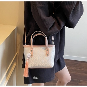 Detail of a chic bucket bag with pink leather trim and elegant geometric jacquard pattern
