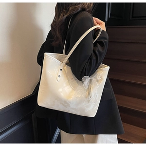 Detailansicht der weißen Marmor-Tote-Bag mit Netzschleifen-Anhänger und Metallkette