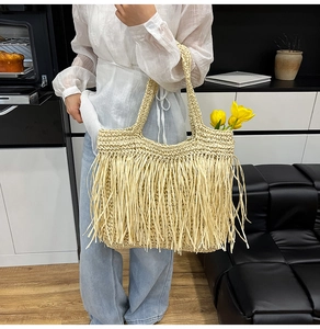 Détail d'un grand sac cabas en paille tissée avec franges décoratives et pompons chics