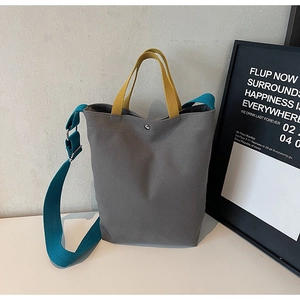 Détail du sac fourre-tout gris avec poignée jaune et bandoulière bleue réglable