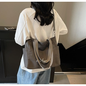 Detailed shoulder view of a charcoal grey canvas tote bag with white artistic lettering