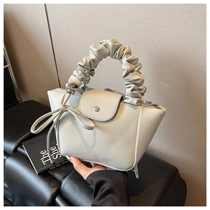 Detail of light gray pleated handbag with decorative bow and textured PU leather