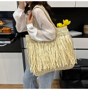 Détail d'un sac cabas en paille bohème avec franges décoratives et large bandoulière