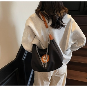 Close-up of black half-moon canvas bag with brown M logo and silver metal chain strap