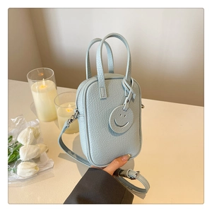 Close-up of mint blue textured leather mini bag with smiley charm and floral decor