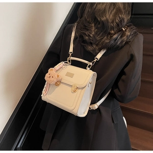 Beige faux leather mini backpack with gold buckle and cute brown bear keychain accessory