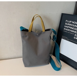 Gros plan détaillé d'un sac cabas en toile grise avec anses jaunes et bandoulière bleue